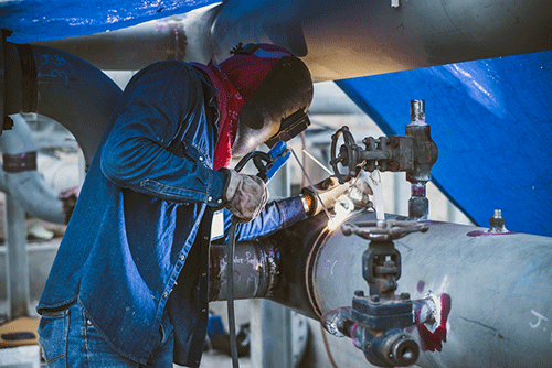 Welder working on a pipe at a construction site