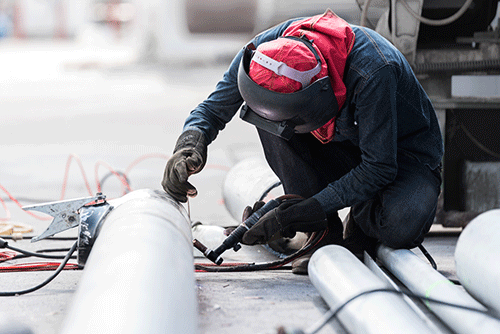 Man working on a pipe in protective work clothing
